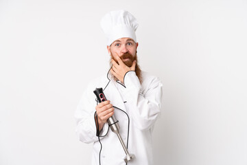 Redhead man using hand blender over isolated white background thinking an idea
