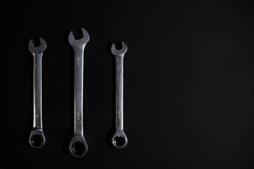 Set of combination wrenches on a black background. Copy space, top view. Three steel open-end keys for repair.
