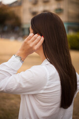 young beautiful girl in a white shirt strokes her hair. She has bright nails