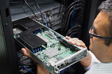 IT expert inserting motherboard on supercomputer server cluster