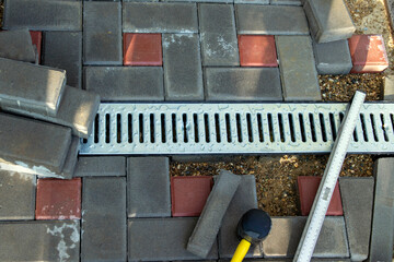 Installation of light metal grating and gutters for drainage of rainwater and paving slabs. Selective focus.