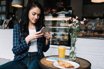 Brunette lady taking photo of food in cafe