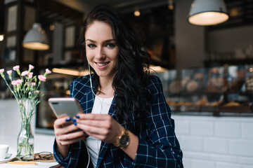 Cheerful woman listening to music while browsing smartphone