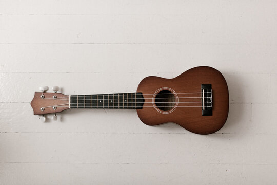 brown ukulele on white floor