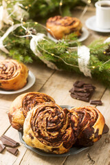 Snail chocolate muffins served with coffee on the background of a wreath of fir branches and cones. Rustic style.