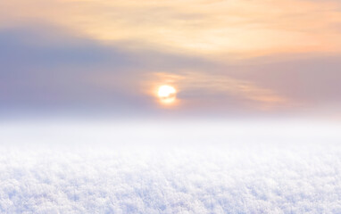 Winter background with snow-covered field and sky during sunset