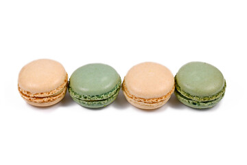 Green pistachio and yellow vanilla French macarons in a row isolated on white background