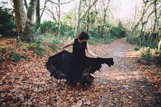 mature woman dancing with a vaporous black dress in the mountain
