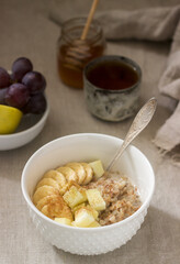 Buckwheat porridge with fruit, green tea, fruit and honey on a linen tablecloth. Rustic style.