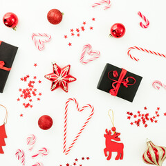 Christmas red composition. Gifts, decoration, candy canes and confetti on white. Flat lay
