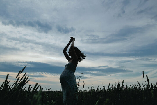 Pregnant woman silhouette in front of sunset clouds