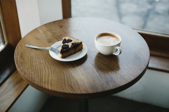latte and pastry on dark wood table in coffee shop