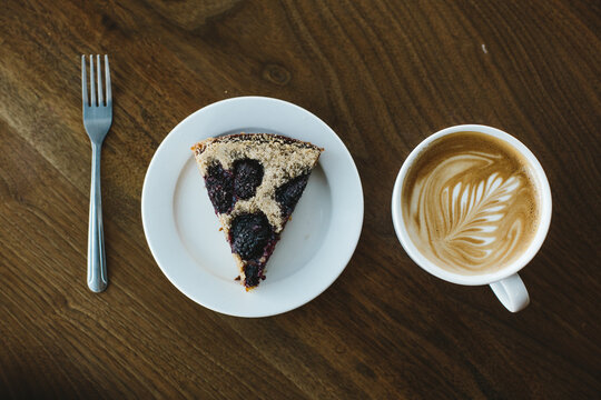 latte and pastry on dark wood table in coffee shop