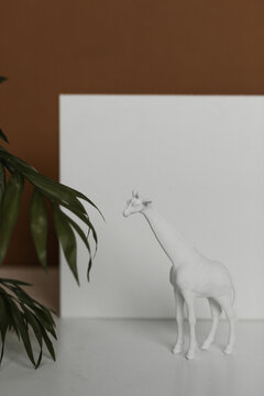 white giraffe figurine with backdrop and plant