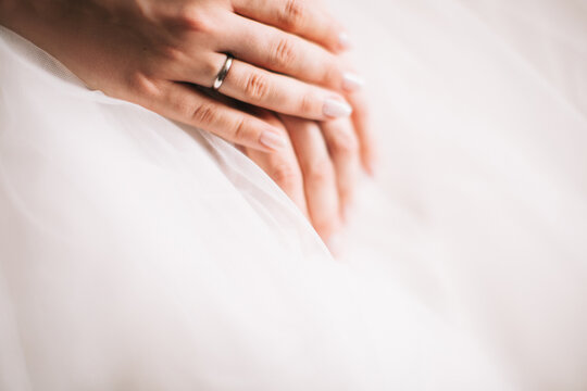 Morning of the bride before the wedding ceremony. Color photo of hands on a wedding dress.