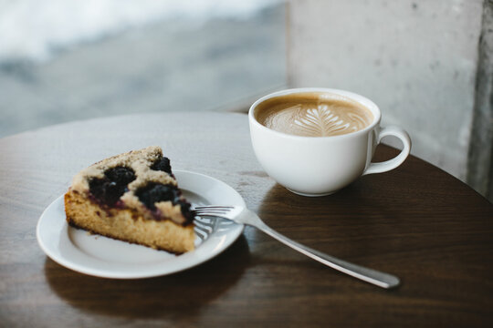 latte and pastry on dark wood table in coffee shop