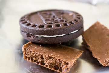Two pieces of milk chocolate with a round chocolate chip cookie close up. Sweets on foil