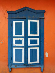 Vintage blue wooden window with shutters on the facade of an old terracotta house