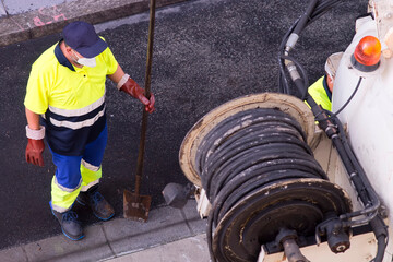 Fototapeta premium sewerage truck service and utility workers for cleaning sewer pipes in city street