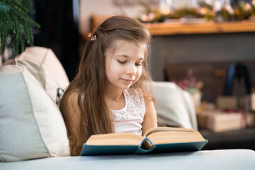 A little girl is reading an interesting book. Education and leisure of children