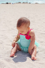 Little baby girl on the beach in a pink a blue bathing suit