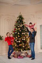 Obraz na płótnie Canvas Happy family decorate the Christmas tree indoors together. Loving family. Merry Christmas and Happy Holidays
