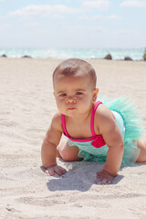 Fototapeta na wymiar Little baby girl on the beach in a pink a blue bathing suit