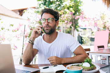Focused man talking on cellphone on summer terrace