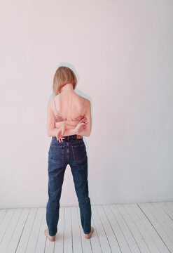 Portrait of a girl in lingerie and jeans on a pink background