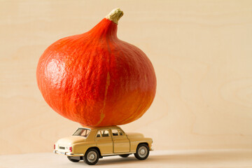 Toy car with pumpkin on roof on light background, Thanksgiving concept