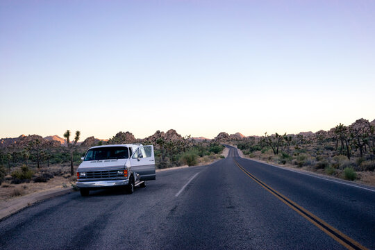 Van parked on the side of a Californian desert highway with it's door open.