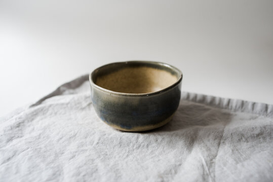 Handmade two toned neutral and light blue modern ceramic pottery cup on white table