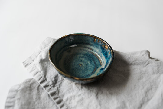 Handmade turquoise ceramic pottery bowl styled on white table and napkin
