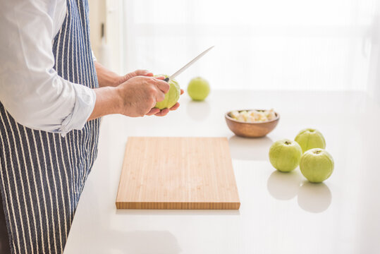 Young man's hands cutting guava fruit in kitchen.