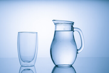 Pitcher with drinking water and a glass with a drink, blue tone