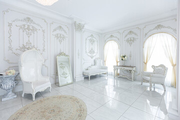 luxury royal posh interior in baroque style. very bright, light and white hall with expensive oldstyle furniture. large windows and stucco ornament decorations on the walls