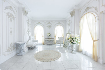 Obraz premium luxury royal posh interior in baroque style. very bright, light and white hall with expensive oldstyle furniture. large windows and stucco ornament decorations on the walls