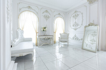 luxury royal posh interior in baroque style. very bright, light and white hall with expensive oldstyle furniture. large windows and stucco ornament decorations on the walls
