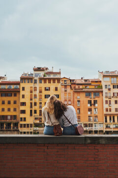 Two tourist girl friends relaxing on historical bridge in Floren