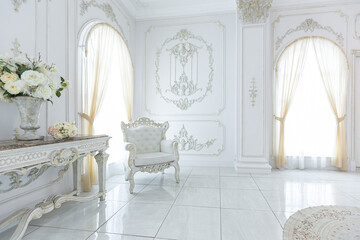 luxury royal posh interior in baroque style. very bright, light and white hall with expensive oldstyle furniture. large windows and stucco ornament decorations on the walls