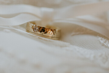 Gold wedding ring on white wedding dress