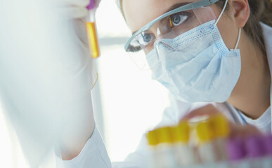 Portrait of pretty female laboratory assistant analyzing a blood sample at hospital