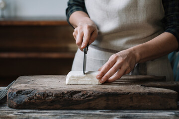 Person slicing feta cheese for spanakopita