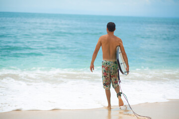 Surfer. Surfing Man With Surfboard Walking On Sandy tropical Beach. Healthy Lifestyle, water activities, Water Sport. Beautiful Ocean.