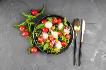 Fresh vegetable salad - tomatoes, lettuce, olives, arugula and olive oil. View from above