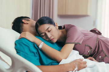 Asian wife embrace sick husband with love to support his illness. patient man sleeping in hospital ward. life insurance, healthcare and medical concept 