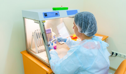 Laboratory assistant sits near special equipment in clinic. Examining bio samples.