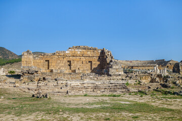 Ruins of Apollo temple in ancient city Hierapolis, Pamukkale, Turkey. Remains of Ploutonion on right side. Also there's antique theater on background. All city objects included in UNESCO List