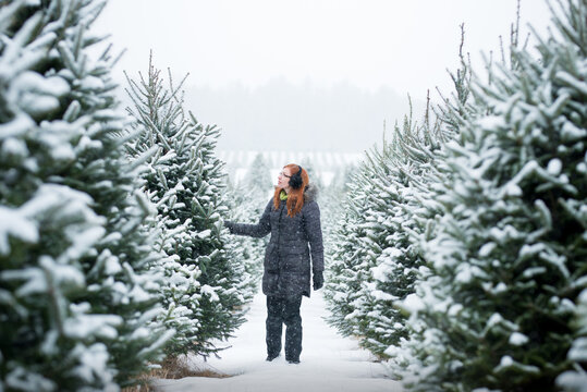 Middle Aged Woman Walking In Snow at Winter Christmas Tree Farm
