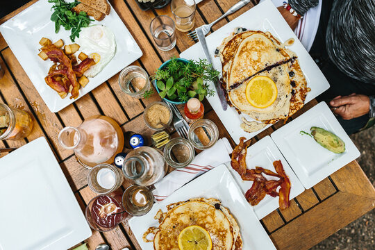 Aerial shot of a table full of breakfast food such as pancakes, eggs, bacon and juice